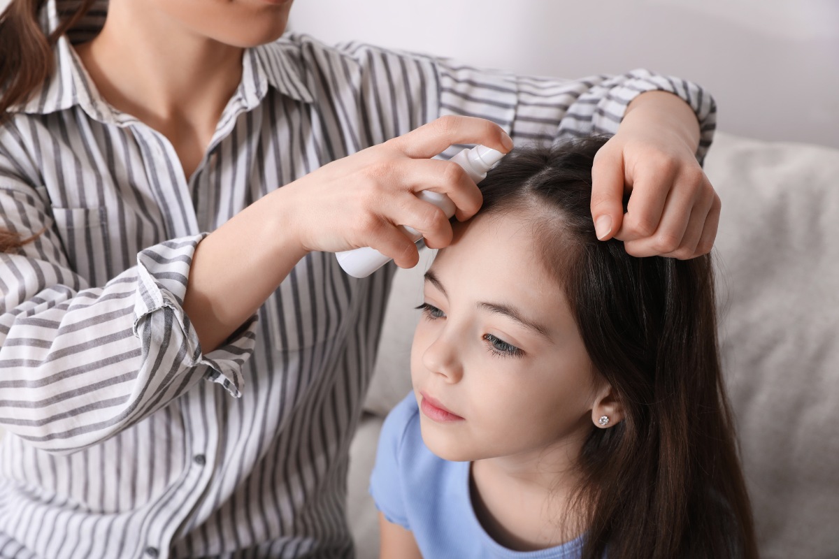 kobieta spryskuje włosy dziewczynki preparatem